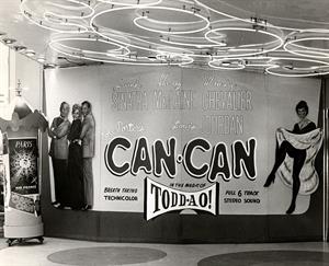A curved wall is covered with a display for the movie Can-Can. On the left is an actress with an actor stand on either side. On the right is a woman dancing. Elaborate neon tubing is visible on the ceiling. A portable display for Air France is on the left. - , Utah