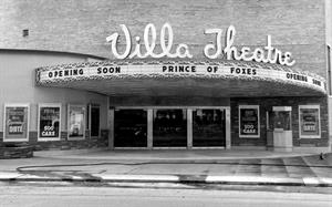 Above the entrance canopy in large cursive letters are the words 'Villa Theatre.' Along the edge of the canopy is an attraction board reading, 'Coming Soon. Prince of Foxes.' The curved wall on the left holds four poster cases. On the right is the ticket booth, with a poster case on either side. - , Utah