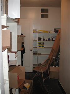 Shelves are built into the left and far walls. A door to the hall is at the far end on the left. A box with empty 35mm film reels sits on the floor, along with other boxes and a chair - , Utah