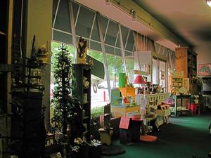 Looking through the store windows onto Highland Drive. The windows lean outward toward the top. Green carpet covers the floors.  Art and craft items are on display. - , Utah