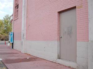 The north exterior wall of the theater. On the right is a single gray door.  In the background on the left is a pay phone, at the end of the wall. - , Utah