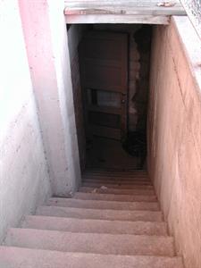 Stairs lead down to shadow, where a door with a missing panel stands open. - , Utah