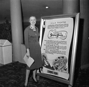 A woman stands next to a display for Sleeping Beauty set between the stairs to the lower lobby and the north hall to the auditorium. - , Utah