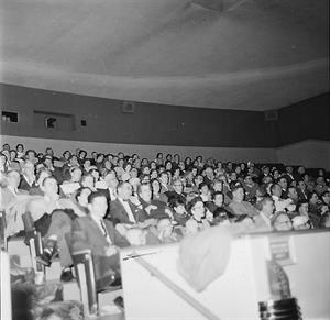 The audience for a showing of South Pacific fills the stadium seating section in 1958.  The back corner of the auditorium has no projection windows, since Cinerama was not installed until 1961.  The ceiling is a lighter color and the surround speakers are more evenly distributed instead of being grouped together. - , Utah