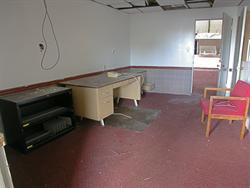 A desk and phone still sit in the office.  The concession stand is visible through the door at the end of the room
