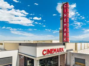 A view level with the roof showing theater entrance below and a vertical blade sign rising above.  A blue sky with clouds fills the background. - , Utah