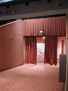 The south hall to the lobby, with curtains partially drawn. Projection windows in the rear wall of the auditorium are visible in the background.