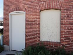 A door and boarded up window at the north end of the west exterior wall. - , Utah