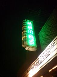 The name of the theater, 'Kamas', is written in green neon on a veritcal blade sign.  - , Utah