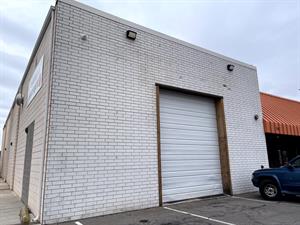 In the middle of a white brick wall is a tall garage door wide enough for a single vehicle. On the side wall, a sign for the Switchpoint Boutique hangs above a walled up doorway. - , Utah