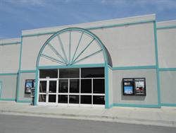 The entrance of the theater has two poster cases on either side and a half-circle neon pattern above.