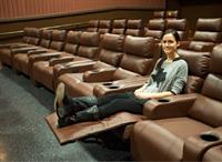 Madelyn Rybczyk, Marketing Manager of Cinemark, shows off the new electric-powered recliners. - , Utah