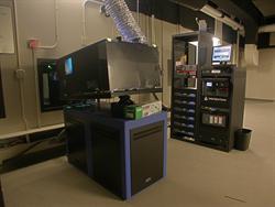 A digital project appears on the left, with a rack of equipment in the background.