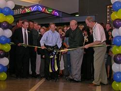 Larry H. Miller tries to cut the ribbon with a large pair of scissors.