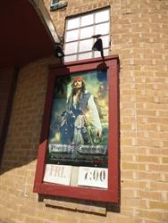 A poster for <span style='font-style: italic;'>Pirates of the Caribbean: On Stranger Tides</span>.  The poster case covers the lower half of a tall window. - , Utah