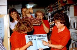 Beverly Mann holds a birthday cake, while Janae and Ruth Simmons look at a card.  Beverly's children, Karlene and Kyle stand in the background. - , Utah