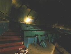 The projection booth is in the middle of the photo, at the rear, with several rows of seating occupying the foreground.  On the left are the stairs of the side aisle. - , Utah