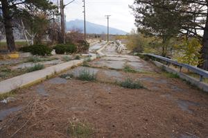 Weeds grow in cracks of an asphalt road with a concrete divider in the middle.   - , Utah