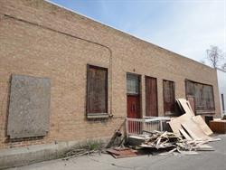 An exit door and ramp on the south exterior wall, along with a few boarded up windows. - , Utah