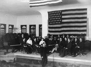 Mose Gudmansen leads an orchestra in a little theater on the east end of the top floor of the College Building. This photo shows the stage before a permanent proscenium arch was installed in 1930. - , Utah