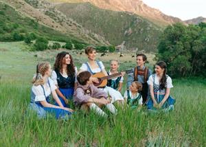 A woman with a guitar sits in a mountain scene, surrounded by seven children. - , Utah