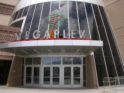 The south entrance of the Megaplex 17 at Jordan Commons has three sets of doors and a tall circular wall with tinted glass windows.  On the left of the theater entrance is the exterior of the Mayan restaurant. - , Utah