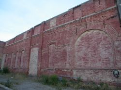 There are several bricked up windows and doorways along the west wall of the building, including one large arched window near the front. - , Utah