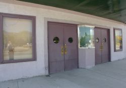 The entrance of the Main Theatre has two sets of double doors, each with a round window.  Between the doors is a single ticket window.  There are two poster cases, one on either side of the entrance. - , Utah