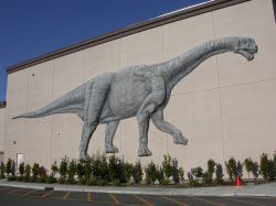 A dinosaur on the southeast outside wall the theater.