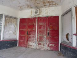 The entrance of the theater has two pairs of red doors, with a poster case on either side.  Above the doors is a speaker. - , Utah