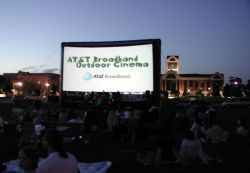 An advertisement for 'AT&T Broadband Outdoor Cinema' displays on the Open Air Cinema screen as a crowd of moviegoers waits for the program to start. - , Utah