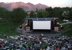 A crowd sits on a hill in front of the Open Air Cinema screen. - , Utah
