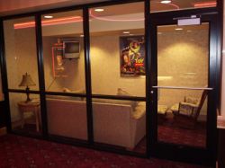 In the main hall of the Redstone Cinemas is a small waiting room with glass walls, a wall-mounted television, a couch and chair, and a poster of 'Toy Story'. - , Utah